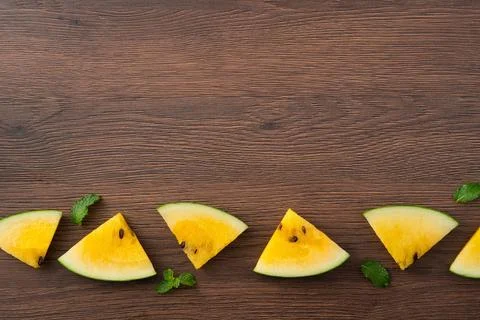 Sliced yellow watermelon pattern flat lay on wooden table background. Stock Photos