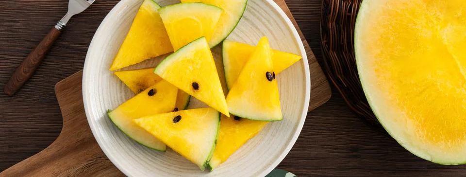 Sliced yellow watermelon pattern flat lay on wooden table background. Stock Photos