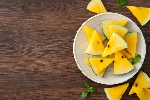 Sliced yellow watermelon pattern flat lay on wooden table background. Stock Photos