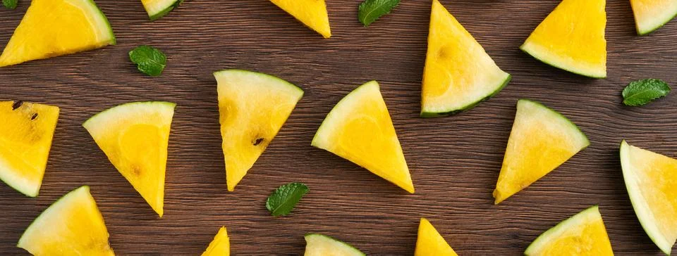 Sliced yellow watermelon pattern flat lay on wooden table background. Stock Photos