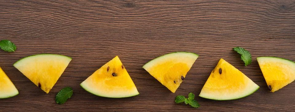 Sliced yellow watermelon pattern flat lay on wooden table background. Stock Photos