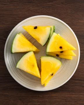 Sliced yellow watermelon pattern flat lay on wooden table background. Stock Photos