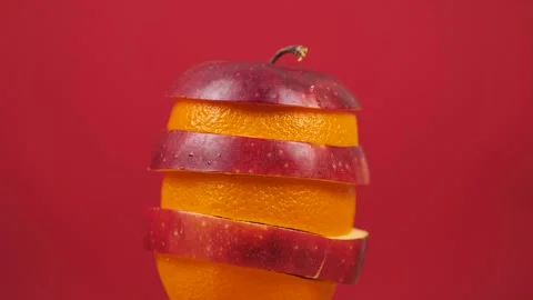 Slices of apple and orange rotates on a red background. Healthy food concept Stock Footage 249079840