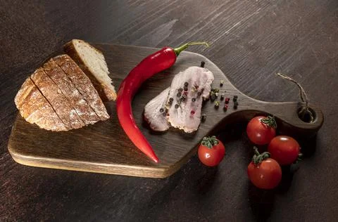 Slices of bacon, bread, tomatoes, pepper on a wooden board Stock Photos