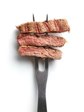 Slices of beef steak on meat fork isolated on white from above Stock Photos