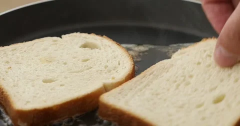 Slices of bread are placed in a frying pan with melted butter. Stock Footage 250177160