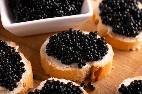Slices of bread with black caviar on rustic dark background Stock Photos