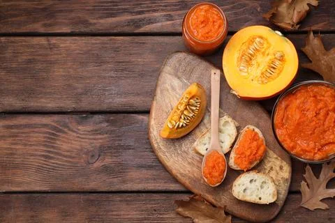 Slices of bread with delicious pumpkin jam and fresh pumpkin on wooden tabl.. Stock Photos