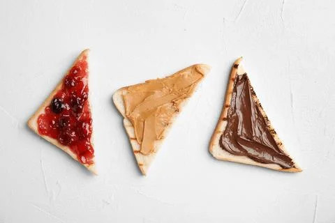 Slices of bread with different spreads on white table, flat lay Foto stock