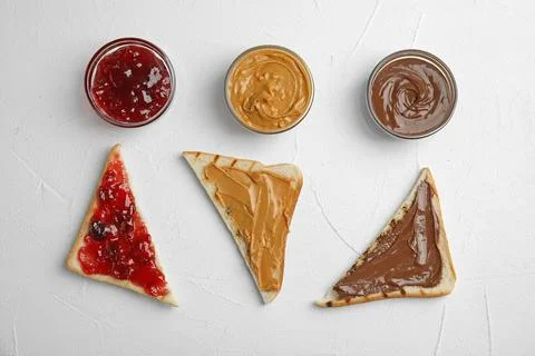 Slices of bread with different spreads on white table, flat lay Foto stock