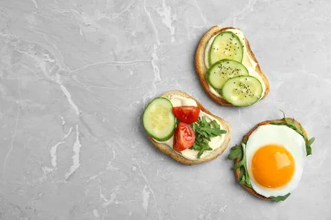 Slices of bread with different toppings on grey marble table, flat lay. Space Foto stock