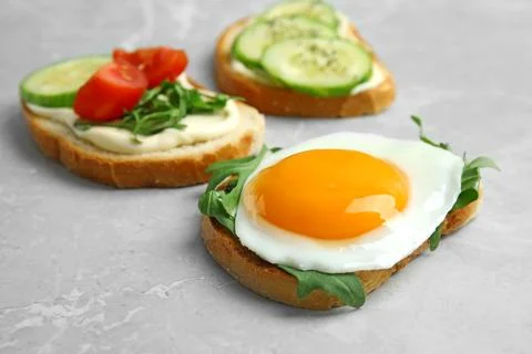 Slices of bread with different toppings on grey marble table Foto stock
