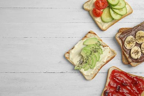 Slices of bread with different toppings on white wooden table, flat lay. Spac Foto stock