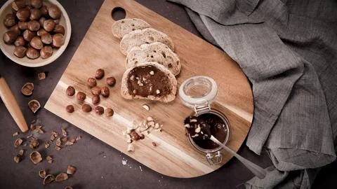 Slices of bread with hazelnut chocolate spread on a wooden board Stock Photos