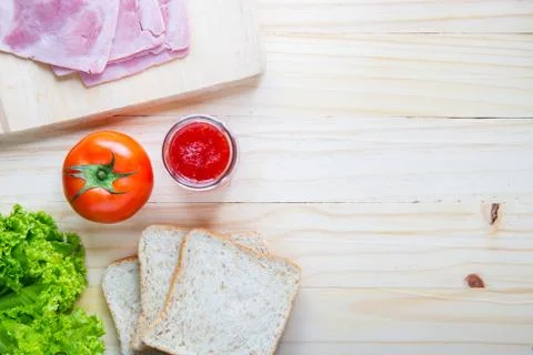 Slices of bread with jam and ham, tamoto, lettuce,  on table with kitchen on  Stock Photos