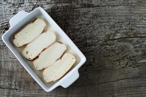 Slices of bread soaking in milk to make torrijas. Copy space. Stock Photos