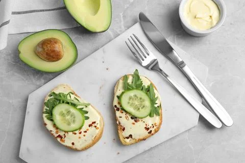 Slices of bread with spread and cucumber on grey marble table, flat lay Stock Photos