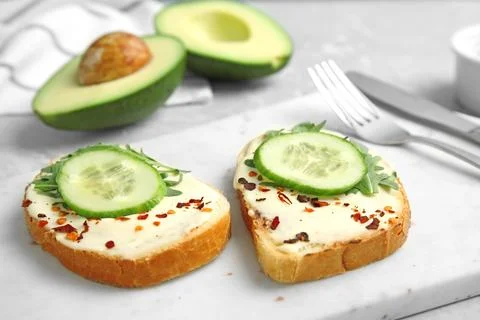 Slices of bread with spread and cucumber on board Stock Photos