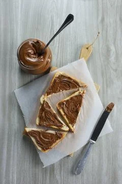 Slices of bread spread with hazelnut praline paste  on wooden cutting board, Stock Photos