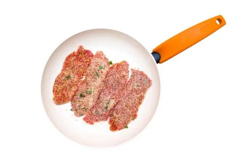 Slices of breaded raw meat in a pan on a white background viewed from above Stock Photos