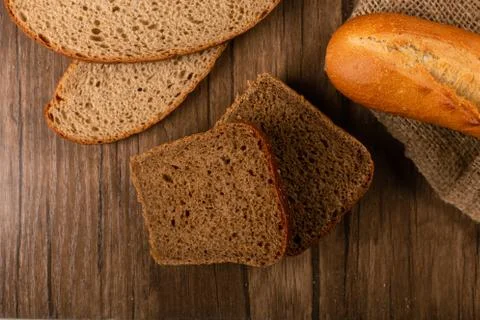 Slices of brown and white bread on kitchen board with baguette Stock Photos