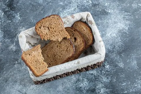 Slices of brown bread on a basket on a gray background Stock Photos