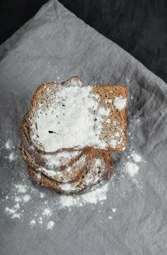 Slices of brown bread with flour on a gray tablecloth Stock Photos