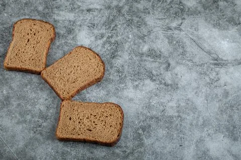 Slices of brown fresh bread on a gray background Stock Photos
