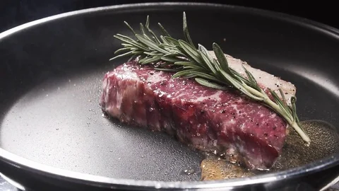 Slices of butter falls on a frying pan to the steak Stock Footage