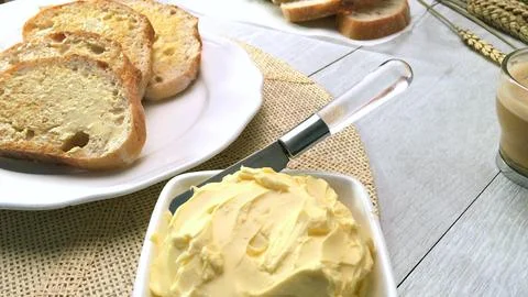 Slices of buttered rustic bread with a bowl of fresh butter Stock Photos