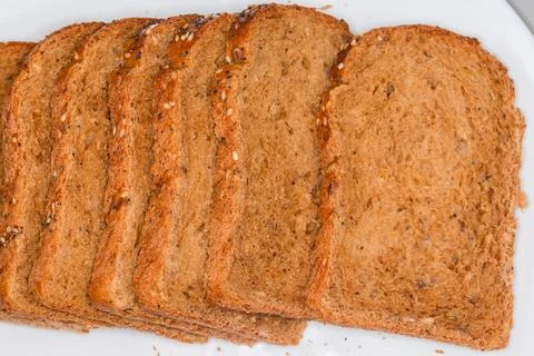 Slices of cereal brown bread on white plate, top view Stock Photos
