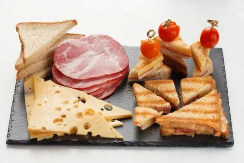 Slices of cheese, ham, bread and hot marinated cherry tomatoes sandwiches Stock Photos
