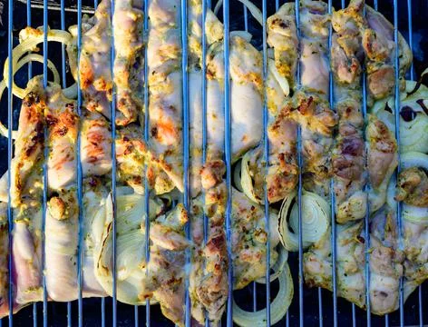 Slices of chicken with array rings are fried on the grill between the lattice Fotos Stock