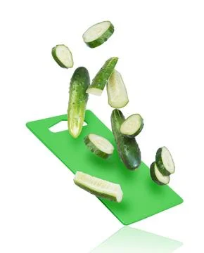Slices of cucumber fall on the kitchen board isolated on white background Stock Photos