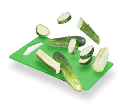Slices of cucumber fall on the kitchen board Stock Photos