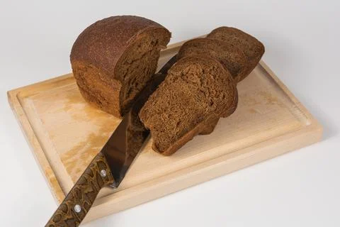 Slices of dark rye bread cut with a knife on a wooden board 스톡 사진