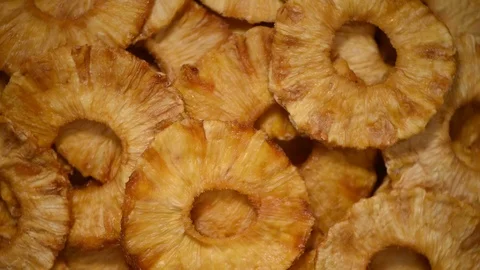 Slices of dried pineapple on rotating background. Top view. Vegan, vegetarian Stock Footage 125371630