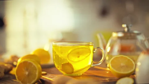 Slices of fresh lemon and ginger gently swirl in a clear glass cup as mornin Stock Footage 331361836