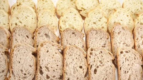 Slices of fresh rye and wheat baguette bread, top view, motion Stock Footage 328575683