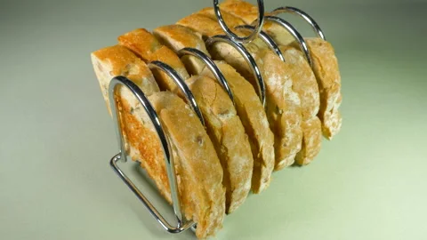 Slices of fresh toast in a rack placed on a green tablecloth. Video stock 172469841