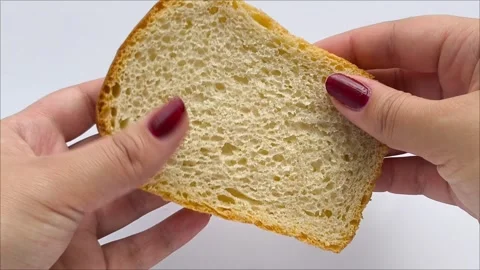 Slices of fresh white bread in the hands of a woman on a white background Stock Footage 311654076
