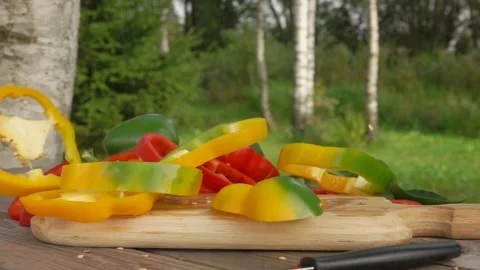 Slices of fresh yellow pepper fall on a wooden board in slow motion Video stock 165870150
