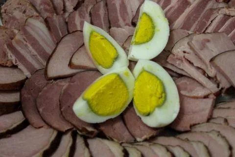 Slices of ham and boiled egg is cut into four parts in a selective focus Stock Photos