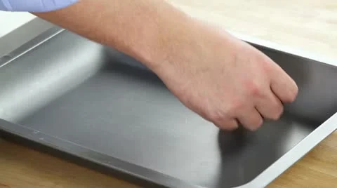 Slices of ham being placed in a preheated roasting tin Stock-Footage 24671597
