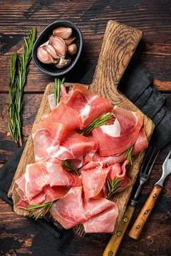 Slices of jamon serrano ham or prosciutto crudo parma on wooden board with Stock Photos