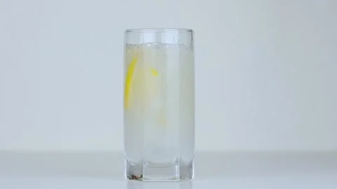 Slices of lemon fall into a transparent glass of water Video stock 229724944