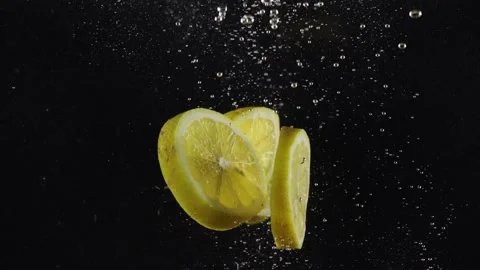 Slices of lemon falling under water with splash isolated over black background Stock Footage 293086200