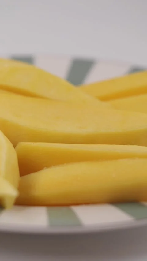 Slices of mango on a plate with green stripes Stock Footage 328619584