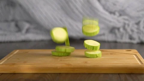 Slices of marrow squash fall on cutting board in slow motion Stock Footage 96492820