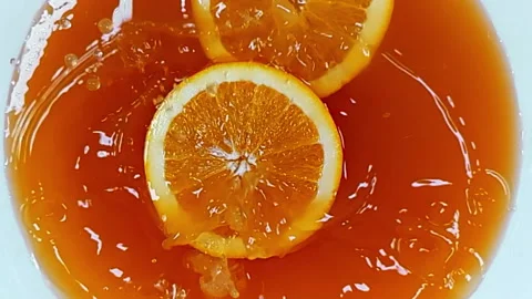 Slices of oranges fall into a white plate on the table Video stock 262759036
